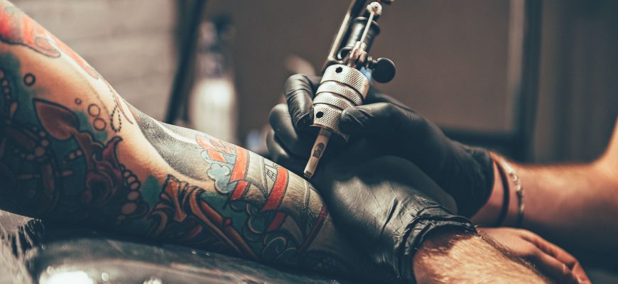 Bild på tatueringsnål och underarm.